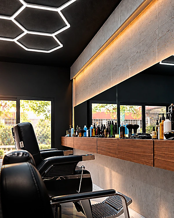 Estaciones con sillones negros, barra de madera con productos y espejo con luz cálida