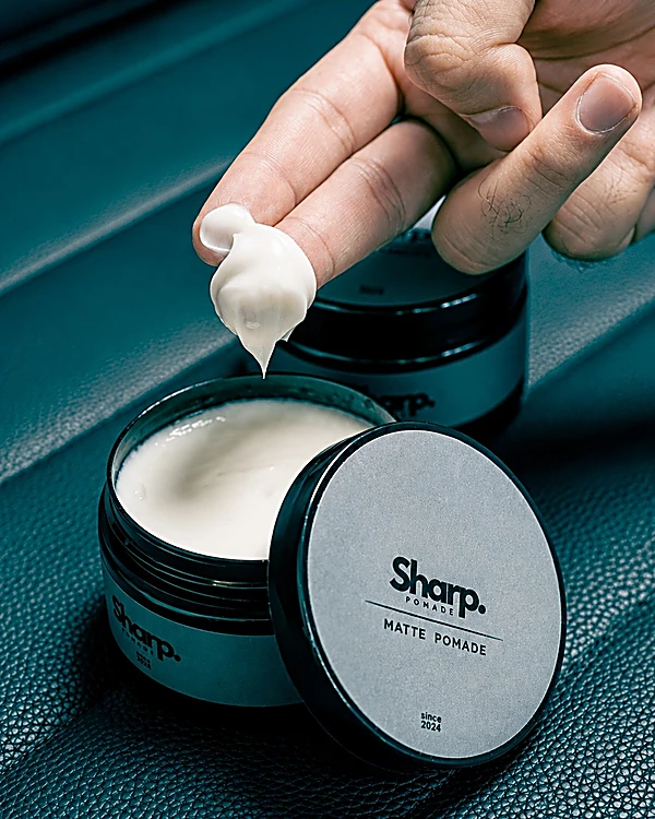 Pomada Sharp Matte abierta mientras un dedo toma producto